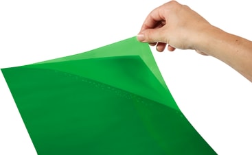Eine Hand zieht eine dünne, hellgrüne, flexible Folie von einer anderen grünen Folie ab und enthüllt kleine Tröpfchen oder Blasen auf der Oberfläche darunter.