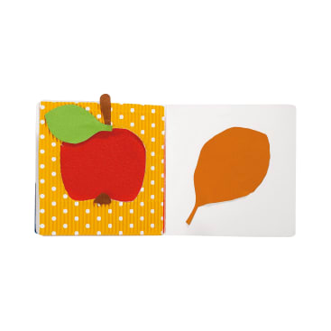 Ein Pappbilderbuch für Kinder zeigt auf der linken Seite einen roten Apfel mit einem grünen Blatt auf einem gelben gepunkteten Hintergrund und auf der rechten Seite eine orangefarbene Blattform auf einem einfarbig weißen Hintergrund.
