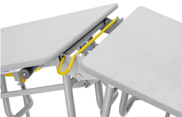 Nahaufnahme von zwei grauen Tischen mit Metallbeinen, die durch einen gelben Sicherheitsverriegelungsmechanismus verbunden sind. Die Tische haben eine strukturierte Oberfläche und sind in einem Winkel zueinander angeordnet.