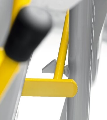 Nahaufnahme eines gelben Metallhebels und eines Verriegelungsmechanismus, der an einem grauen Metallrahmen befestigt ist, mit unscharfem Hintergrund.