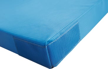 Nahaufnahme der Ecke einer blauen, rechteckigen, gepolsterten Matte mit strukturierter Oberfläche und verstärkten Nähten an den Rändern.