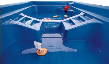 Ein blauer Wasserspieltisch aus Kunststoff mit flachem Wasser, kleinen schwimmenden Spielzeugen, darunter ein Spielzeugboot mit weißem Segel, und einigen Wassertropfen auf der Oberfläche.