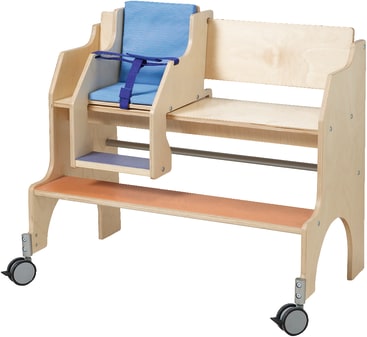 Ein adaptiver Holzstuhl mit Rollen, einem blau gepolsterten Sitz mit Gurt, einer integrierten Fußstütze und einer zusätzlichen Sitzbank auf der rechten Seite.