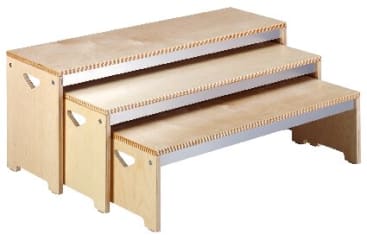 Ein dreistufiger Tritthocker aus Holz mit ausgeschnittenen Griffen an den Seiten. Jede Stufe ist schrittweise höher, und der Hocker hat eine helle Holzoberfläche mit sichtbaren Fugen an den Ecken.