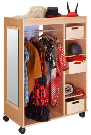 Ein hölzerner Verkleidungsschrank auf Rädern bietet Platz für Kostüme auf Bügeln, Hüte und Accessoires auf Regalen und in Fächern. An einer Seite ist ein Spiegel angebracht, und verschiedene bunte Kostüme und Requisiten sind zu sehen.