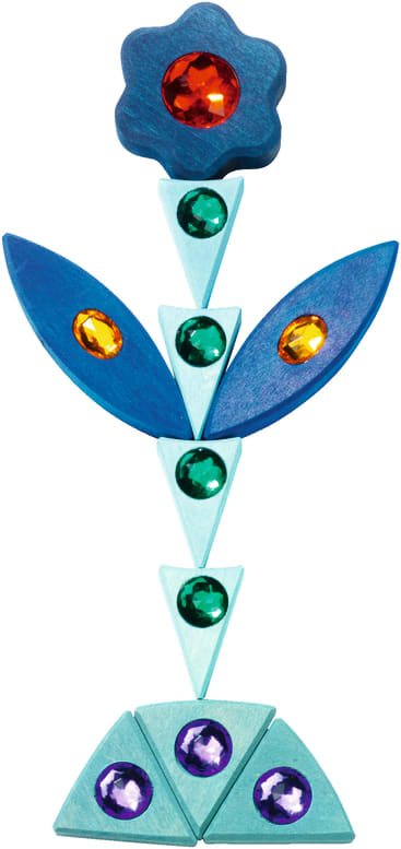 Eine geometrische Blume aus blauen und grünen Holzformen mit bunten, edelsteinähnlichen Verzierungen, darunter ein roter Edelstein in der Mitte der Blume und kleinere grüne, gelbe und violette Edelsteine auf den Blütenblättern, dem Stiel und der Basis.