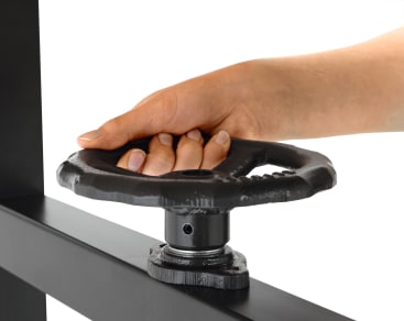 Eine Hand ergreift und dreht ein schwarzes Metallrad, das an einer horizontalen Metallstange befestigt ist, vor einem weißen Hintergrund.