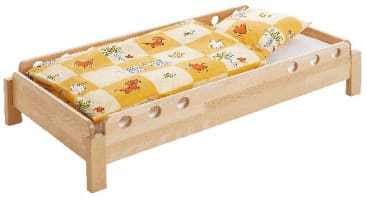 Ein hölzerner Bettrahmen mit abgerundeten Kanten und Löchern in den Seitenteilen, abgebildet mit einer gelb-weiß karierten Decke mit Tiermotiven und einem passenden Kopfkissen.
