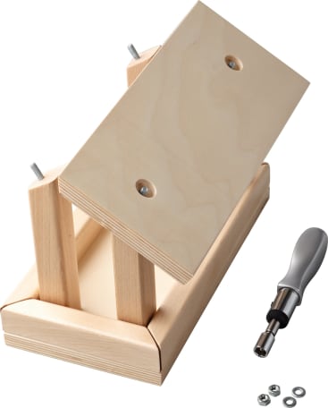Eine kleine Holzbank wird zusammengebaut, wobei ein Schraubenzieher, Schrauben und Unterlegscheiben in der Nähe liegen. Die Bank besteht aus hellen Holzbrettern und zwei teilweise eingesteckten Bolzen.