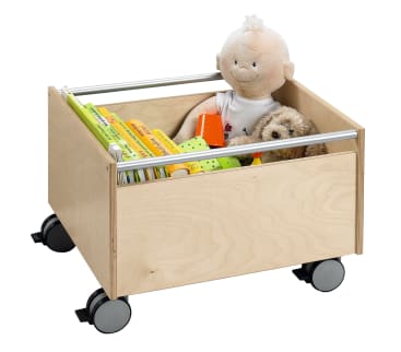 Eine Holzkiste auf Rädern enthält Kinderbücher, eine Plüschpuppe, einen Plüschhund und ein paar bunte Spielsachen. Die Kiste hat oben Metallstangen und steht auf einem weißen Hintergrund.