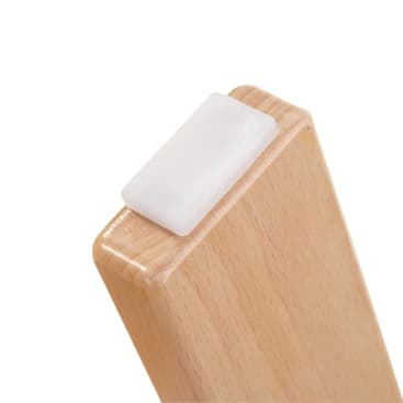Nahaufnahme der Ecke eines Möbelbeins aus hellem Holz, an dessen Ende ein rechteckiges weißes Kunststoff- oder Gummipolster befestigt ist, das wahrscheinlich als Bodenschutz dient.