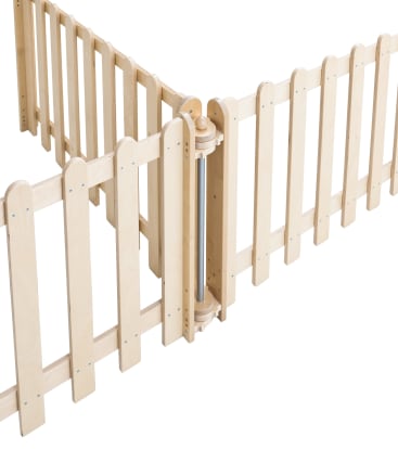 Ein Sicherheitstor aus Holz mit vertikalen Lamellen bildet eine Eckbarriere. Das Tor hat einen sicheren Scharnier- und Verriegelungsmechanismus an der Eckverbindung. Das Holz hat eine helle Farbe und die Paneele sind gleichmäßig verteilt.