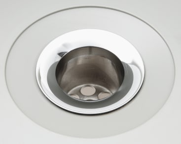 Nahaufnahme eines sauberen, leeren Spülbeckenablaufs aus Edelstahl mit reflektierender Oberfläche und sichtbaren Ablauflöchern am Boden.