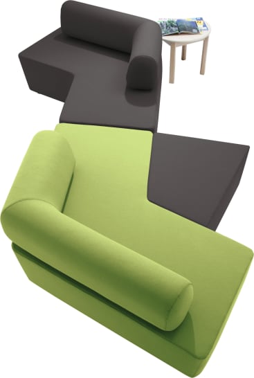 Zwei moderne, L-förmige Sofas - ein grünes und ein dunkelgraues - sind in einem Zickzack-Muster angeordnet. Ein kleiner, runder Beistelltisch aus Holz mit mehreren Zeitschriften steht daneben.