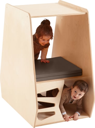 Zwei kleine Kinder spielen in und um eine hölzerne Spielstruktur mit einem Kissen auf einer oberen Ebene und ausgeschnittenen Formen auf einer unteren Ebene. Ein Kind steht oben und das andere krabbelt durch den unteren Teil.