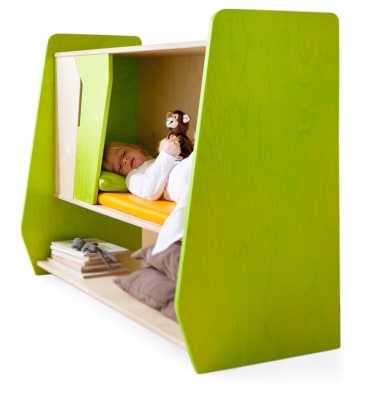 Ein Kind liegt auf einer Matratze in einem grünen Etagenbett aus Holz. Das Bett hat oben ein offenes Fach und unten ein Regal mit Büchern und Kissen. Das Kind hält ein Stofftier und blickt nach vorne.