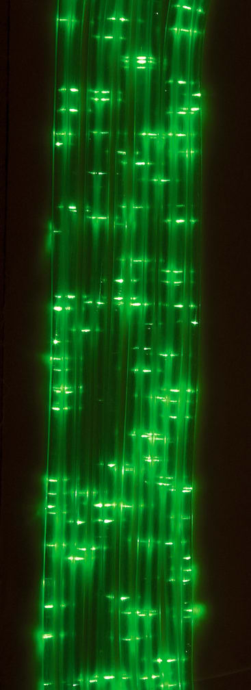 Vertikale, parallele Reihen grüner LED- oder Glasfaserleuchten leuchten und reflektieren auf einem dunklen Hintergrund und erzeugen ein Muster aus hellen Punkten und Linien.