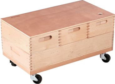 Eine rechteckige Aufbewahrungsbox aus Holz mit drei Schubladen an der Vorderseite, keilgezinkter Konstruktion, einem flachen Deckel, seitlichen Griffen und vier schwarzen Rollen. Die Box wirkt stabil und mobil.