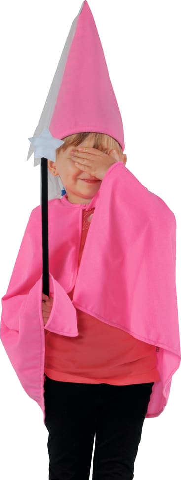 Ein als Fee oder Zauberer gekleidetes Kind in einem leuchtend rosafarbenen Outfit und mit einem spitzen Hut hält einen Zauberstab und bedeckt mit einer Hand sein Gesicht.