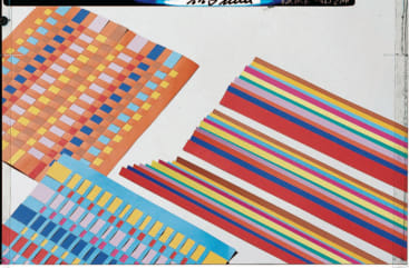 Vier Blätter bunt gemustertes Papier mit gewebten und gestreiften Mustern sind auf einer weißen Fläche angeordnet. Zu den Mustern gehören Schachbrettmuster und parallele Linien in verschiedenen leuchtenden Farben.