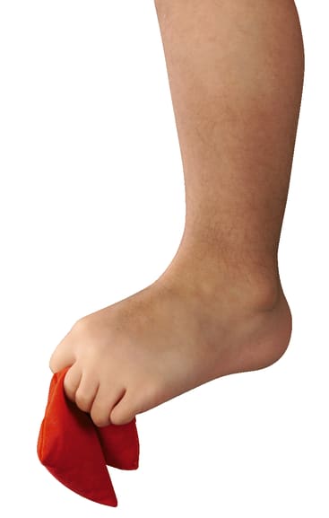 Ein nackter Fuß, der mit den Zehen ein rotes Tuch umklammert, vor einem weißen Hintergrund.