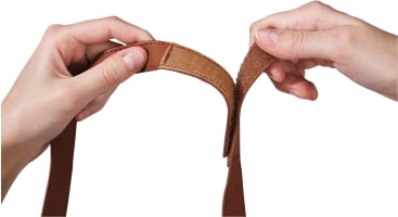 Zwei Hände ziehen die Enden eines braunen Bandes mit einem Klettverschluss auseinander.