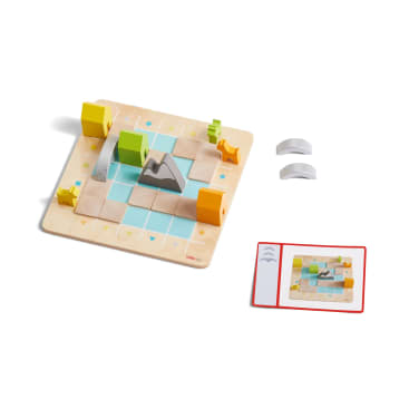 Ein Brettspiel aus Holz mit einem Raster, Bergen, gelben Tierfiguren, farbigen Blöcken, zwei gebogenen grauen Spielsteinen und einer Karte, die eine kleinere Version des Bretts und eine Anleitung enthält.
