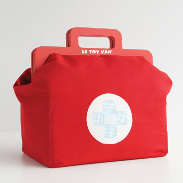 Eine rote medizinische Spielzeugtasche mit Henkel und einem weißen Kreis mit blauem Kreuz auf der Vorderseite. Auf dem Henkel ist der Schriftzug LE TOY VAN aufgedruckt. Die Tasche ist auf einem schlichten weißen Hintergrund abgebildet.