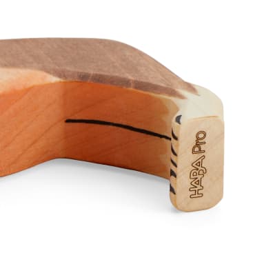 Nahaufnahme eines Holzobjekts mit geschwungenen Kanten, das an einem Ende den eingravierten Text "HABA Pro" aufweist. Das Holz zeigt eine natürliche Maserung und eine dunkle, geschwungene Linie in der Nähe der Ecke.
