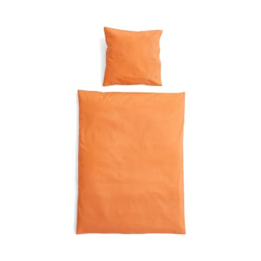 Ein ordentlich arrangiertes orangefarbenes Kissen und eine passende orangefarbene Bettdecke werden von oben gesehen auf einem weißen Hintergrund gezeigt.