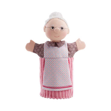 Eine Handpuppe, die wie eine ältere Frau aussieht, mit weißem Haar in einem Dutt, einer Brille, einer gemusterten Bluse und einer rosa-weißen Schürze.
