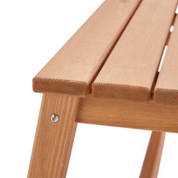 Nahaufnahme einer Holzbank oder eines Holzstuhls, die die Ecke der Sitzfläche aus parallelen Holzlatten und eine Schraube zur Befestigung des Rahmens zeigt.