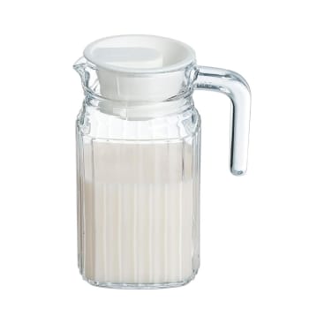 Ein klarer Glaskrug mit vertikalen Rillen, der bis zur Hälfte mit einer weißen Flüssigkeit, möglicherweise Milch, gefüllt und mit einem weißen Kunststoffdeckel verschlossen ist, ist vor einem schlichten weißen Hintergrund abgebildet.