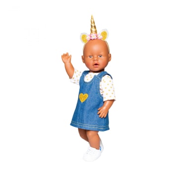 Eine Babypuppe, die ein blaues Jeanskleid mit einem gelben Herz, ein weißes Hemd mit goldenen Punkten, weiße Turnschuhe und ein goldenes Einhorn-Stirnband mit Ohren und Blumen trägt. Der rechte Arm der Puppe ist angehoben.