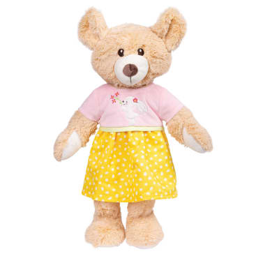 Ein hellbrauner Teddybär, der ein rosa Oberteil mit weißem Hasenmuster und einen gelben Rock mit weißen Tupfen trägt, steht aufrecht vor einem weißen Hintergrund.