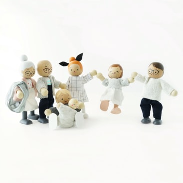 Sechs Holzpuppen, die eine Familie mit zwei Erwachsenen, zwei Kindern, einem älteren Mann und einer älteren Frau mit grauem Haar in einem Dutt darstellen, stehen und sitzen zusammen auf einem weißen Hintergrund.