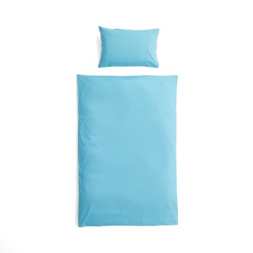 Ein ordentlich gemachtes Bett mit einem hellblauen Kissen am Kopfende und einer passenden hellblauen Bettdecke auf weißem Hintergrund. Das Bettzeug ist einfach und ungemustert.