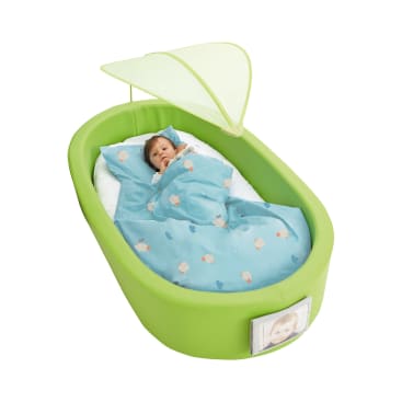 Ein Baby liegt in einem grünen, ovalen, tragbaren Kinderbett mit einer blauen, mit kleinen Mustern bedeckten Decke unter einem hellgrünen Baldachin. In einer Tasche an der Außenseite des Kinderbettes befindet sich ein Foto eines Babys.