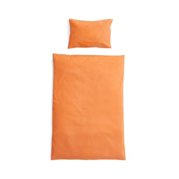 Ein orangefarbenes Kissen und eine passende orangefarbene Decke liegen flach auf einem weißen Hintergrund, von oben fotografiert.