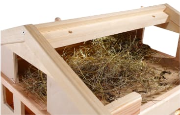 Eine Nahaufnahme eines mit trockenem Heu gefüllten Holzstalls. Der Stall ist oben offen und gibt den Blick auf die Stroheinstreu im Inneren frei. Das Holz hat eine helle Farbe und die Struktur wirkt neu und sauber.