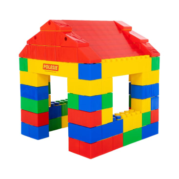 Ein Spielzeughaus aus großen, ineinandergreifenden Plastiksteinen in den Farben Rot, Gelb, Blau und Grün, mit offenen Fenstern und einem roten Schrägdach. Die Bausteine sind in wechselnden Farben gestapelt.
