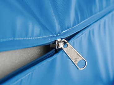 Nahaufnahme eines metallischen Reißverschlusses, der teilweise auf einem blauen Stoff geöffnet ist. Auf dem Reißverschlusszug ist das Wort OPTI eingraviert. Der Hintergrund und der umgebende Bereich sind ebenfalls blau.