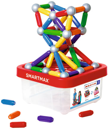 Ein Satz bunter magnetischer Baustäbe und silberner Kugeln ist auf einem durchsichtigen SmartMax-Aufbewahrungsbehälter aus Kunststoff mit rotem Deckel gestapelt. Drei magnetische Stäbe liegen neben dem Behälter.