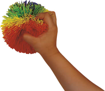 Eine Hand, die einen bunten, stacheligen Ball mit gelben, orangefarbenen, roten, grünen, blauen und lila Gummisträngen vor einem weißen Hintergrund zusammendrückt.