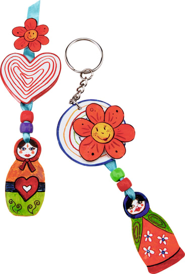 Zwei bunte Schlüsselanhänger mit Perlen; einer hat eine rote Blume und ein Herz, der andere eine rote Blume und runde Formen. Beide sind mit gemalten Matrjoschka-Puppenmotiven in Rot, Grün und Blau versehen.