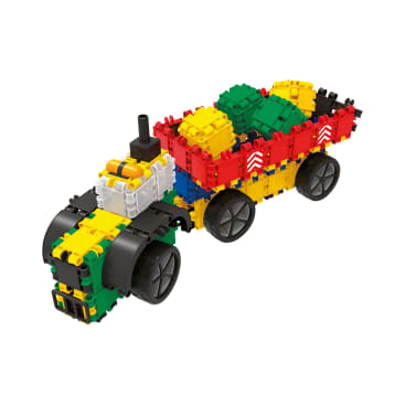 Ein Spielzeugtraktor mit Anhänger aus ineinander greifenden Kunststoffblöcken in Grün, Gelb, Schwarz, Rot und Weiß, mit großen Rädern und grünen und gelben Blockformen im Inneren des Anhängers.