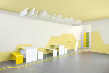 Ein moderner, minimalistischer Raum mit weißen und gelben geometrischen Möbeln, darunter Tische, Bänke und Schränke. Die Wände und die Decke sind in gelben und weißen Farbblöcken gehalten, mit Linien, die über den Boden und an der Wand entlang laufen.