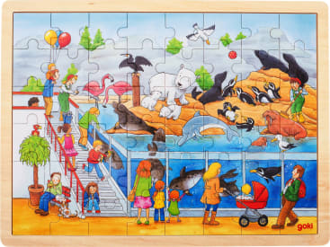 Ein farbenfrohes Puzzle zeigt eine geschäftige Zoo-Szene mit Menschen, die verschiedene Tiere wie Robben, Pinguine, einen Eisbären, Flamingos, Delfine, ein Walross und verschiedene Vögel in und um ein großes Wassergehege beobachten.