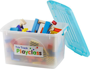 Ein durchsichtiger Plastikbehälter mit blauem Deckel, der teilweise geöffnet ist, enthält verschiedene bunte Holzspielzeugblöcke und -teile. Auf dem Etikett des Behälters steht "Trix Track Playclass".