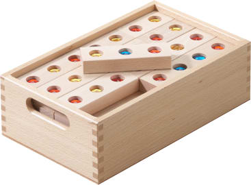 Eine Holzkiste mit rechteckigen Holzklötzen, die jeweils mit kleinen farbigen Glas- oder Kunststoffeinlagen in Rot, Blau und Gelb versehen sind. Die Kiste hat eine Griffaussparung und ist übersichtlich geordnet und sichtbar gestapelt.